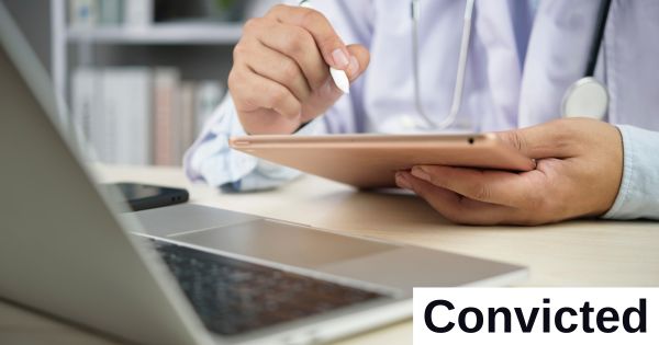 A person holds a tablet with a computer nearby.