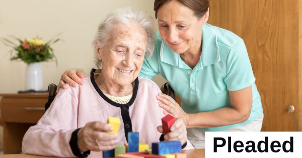 A younger woman leans toward an older woman who is playing with blocks.