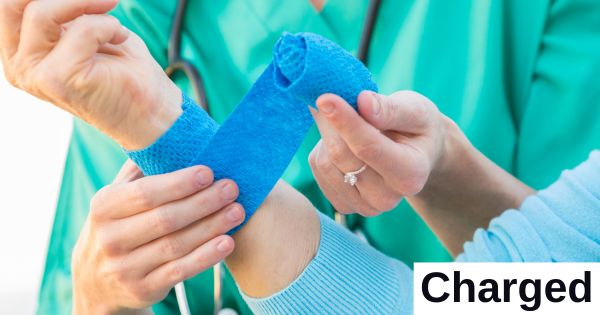 A medical provider wraps a wrist in a blue dressing.