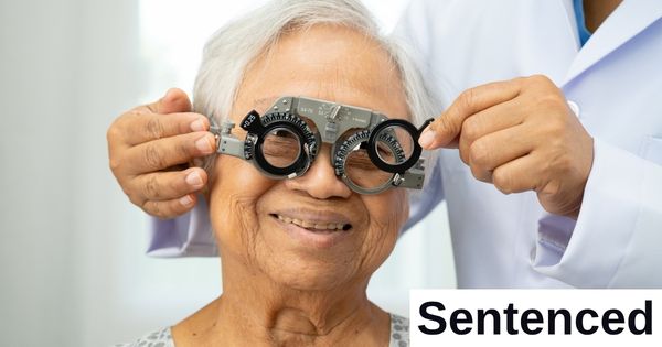 A doctor fits glasses on a patient.